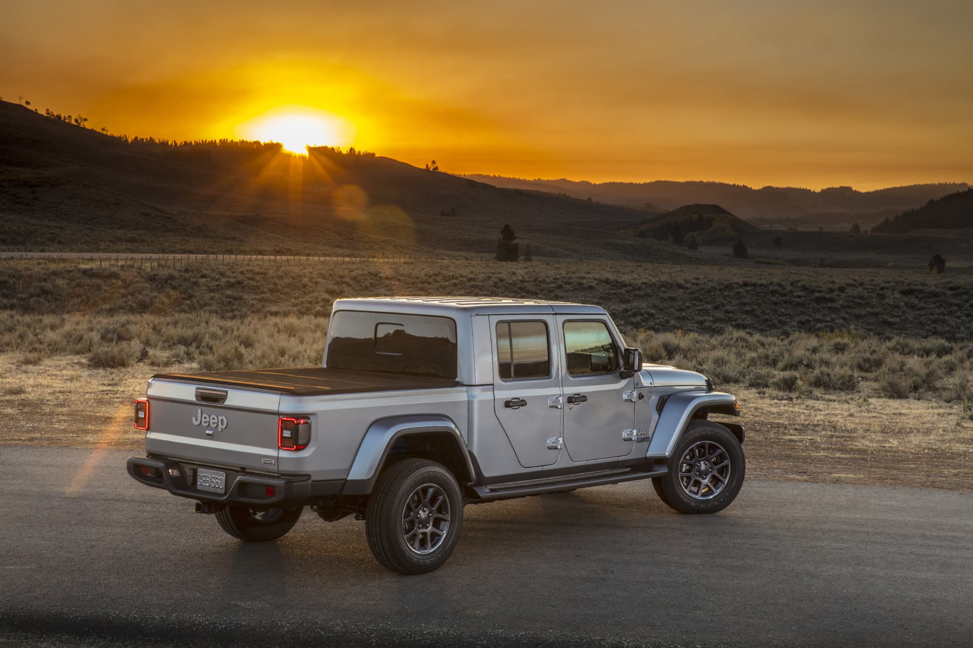 Jeep Gladiator en movimiento con un atardecer de fondo, mostrando su perfil lateral
