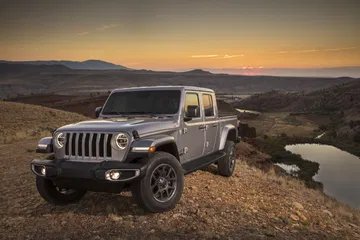 Vista lateral del Jeep Gladiator en un entorno montañoso al atardecer.