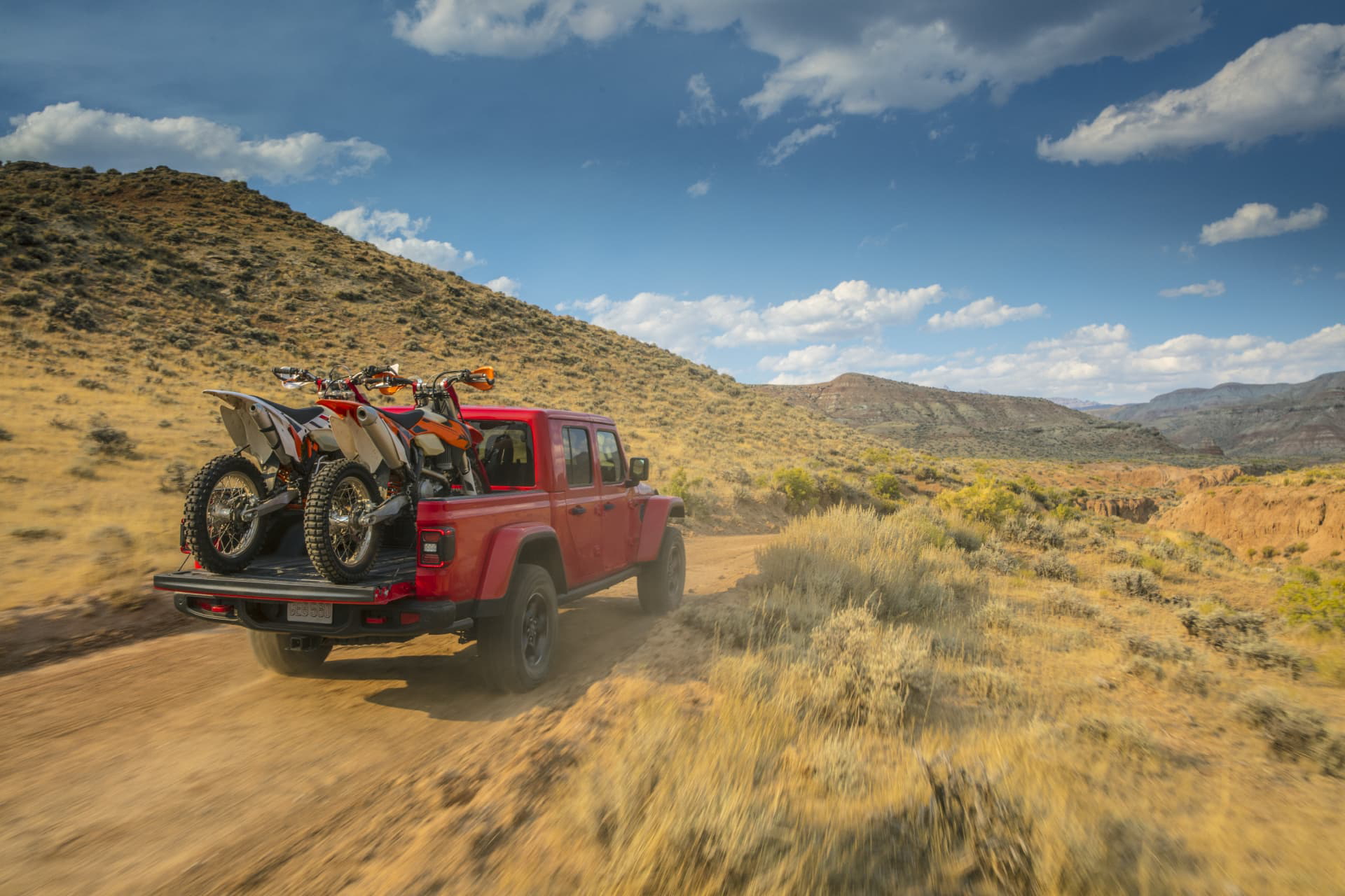Jeep Gladiator en plena acción sobre terreno accidentado, ideal para aventureros.