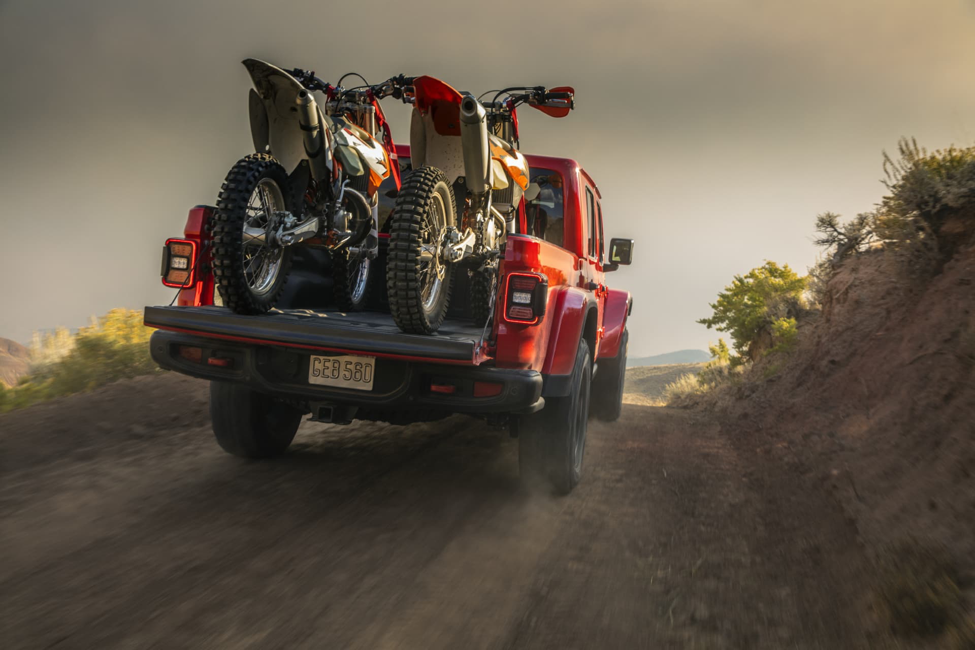 Vista dinámica de un Jeep Gladiator en terreno de aventura con maletero abierto.