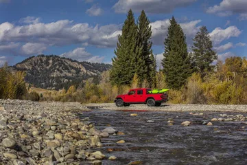 Vista lateral del Jeep Gladiator cruzando un río, destacando su capacidad todoterreno.