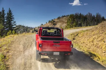 Jeep Gladiator enfrentando un camino de montaña, vista trasera y lateral.