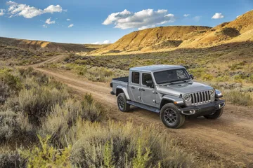 Vista lateral del Jeep Gladiator avanzando por un terreno irregular.