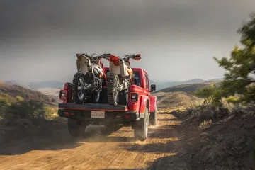 Un Jeep Gladiator transportando bicicletas y equipo por terreno montañoso.