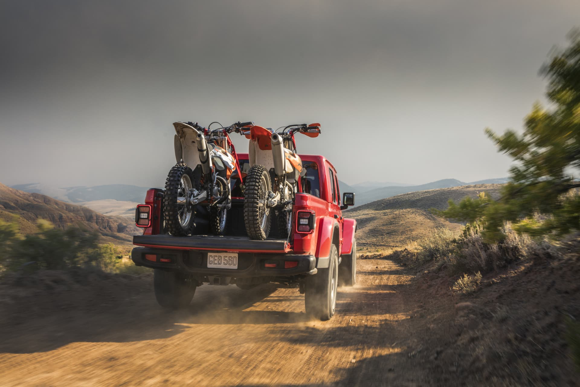 Un Jeep Gladiator transportando bicicletas y equipo por terreno montañoso.