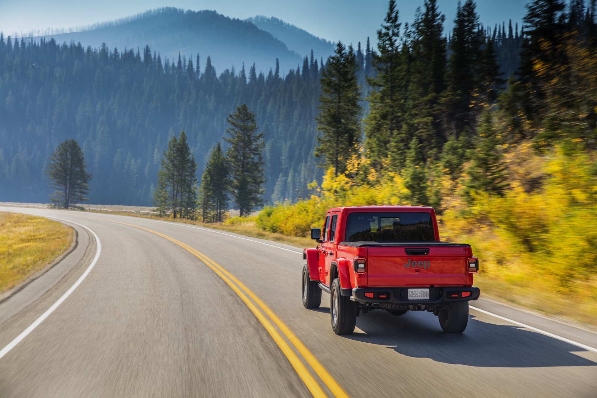 Jeep Gladiator en carretera de montaña, vista lateral y trasera dinámica.