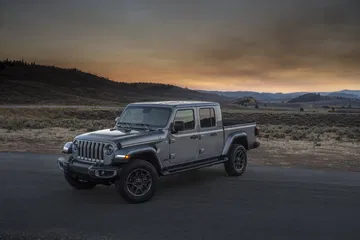 Vista lateral de un Jeep Gladiator al crepúsculo, destacando su silueta y diseño robusto.