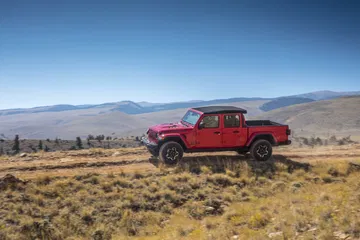 Jeep Gladiator perfilado en terreno rústico, destacando su adaptabilidad todo terreno.