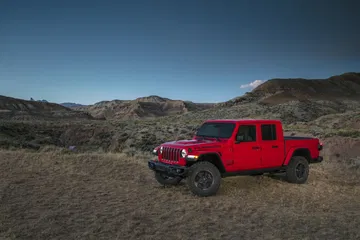 Vista lateral del Jeep Gladiator en un entorno de montaña, destacando su perfil robusto.