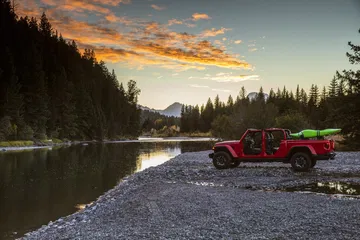 Jeep Gladiator aparcado al lado de un lago, mostrando su perfil lateral y capacidades off-road.