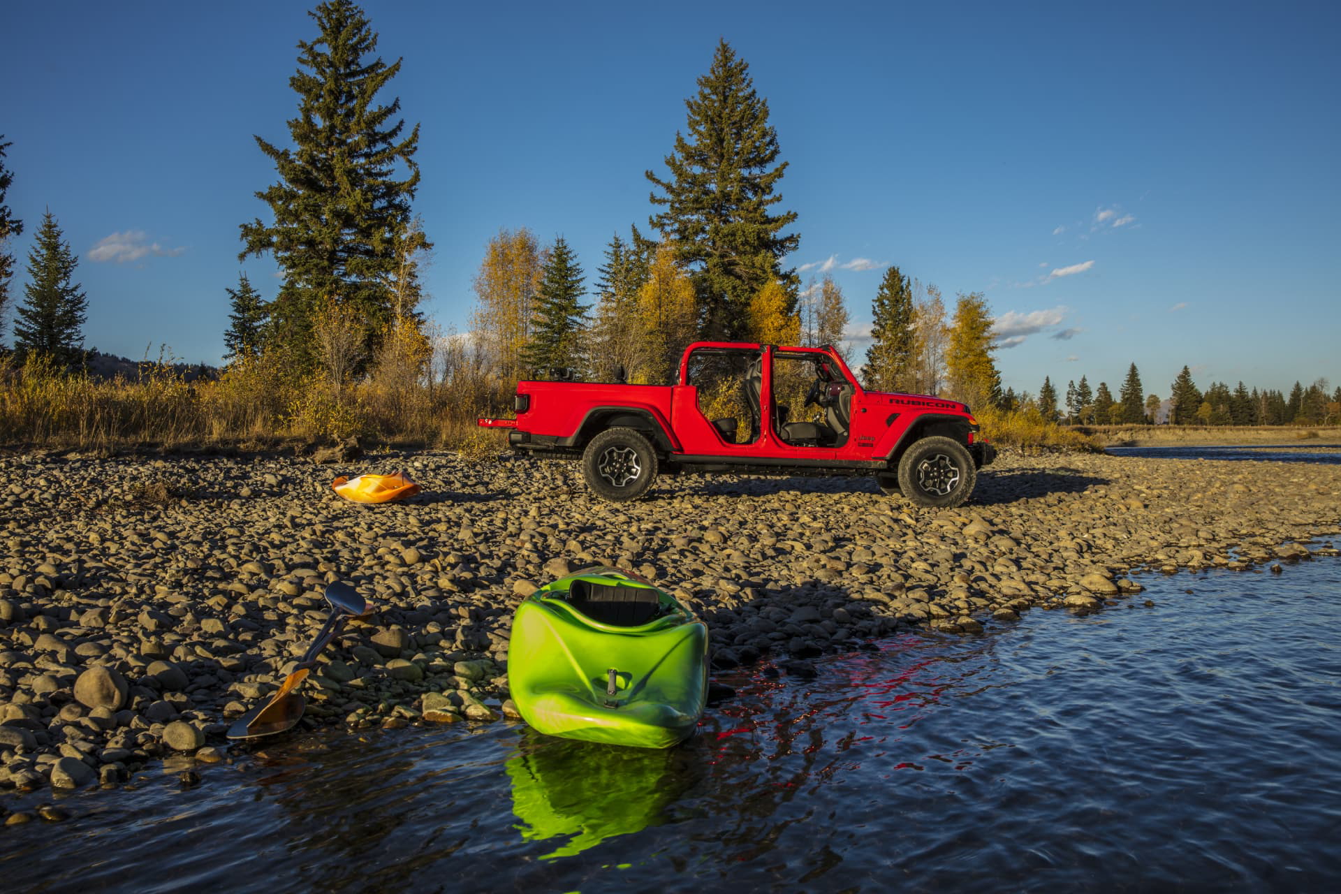 Jeep Gladiator aparcado a orillas de un río, destacando su perfil lateral y capacidad off-road.