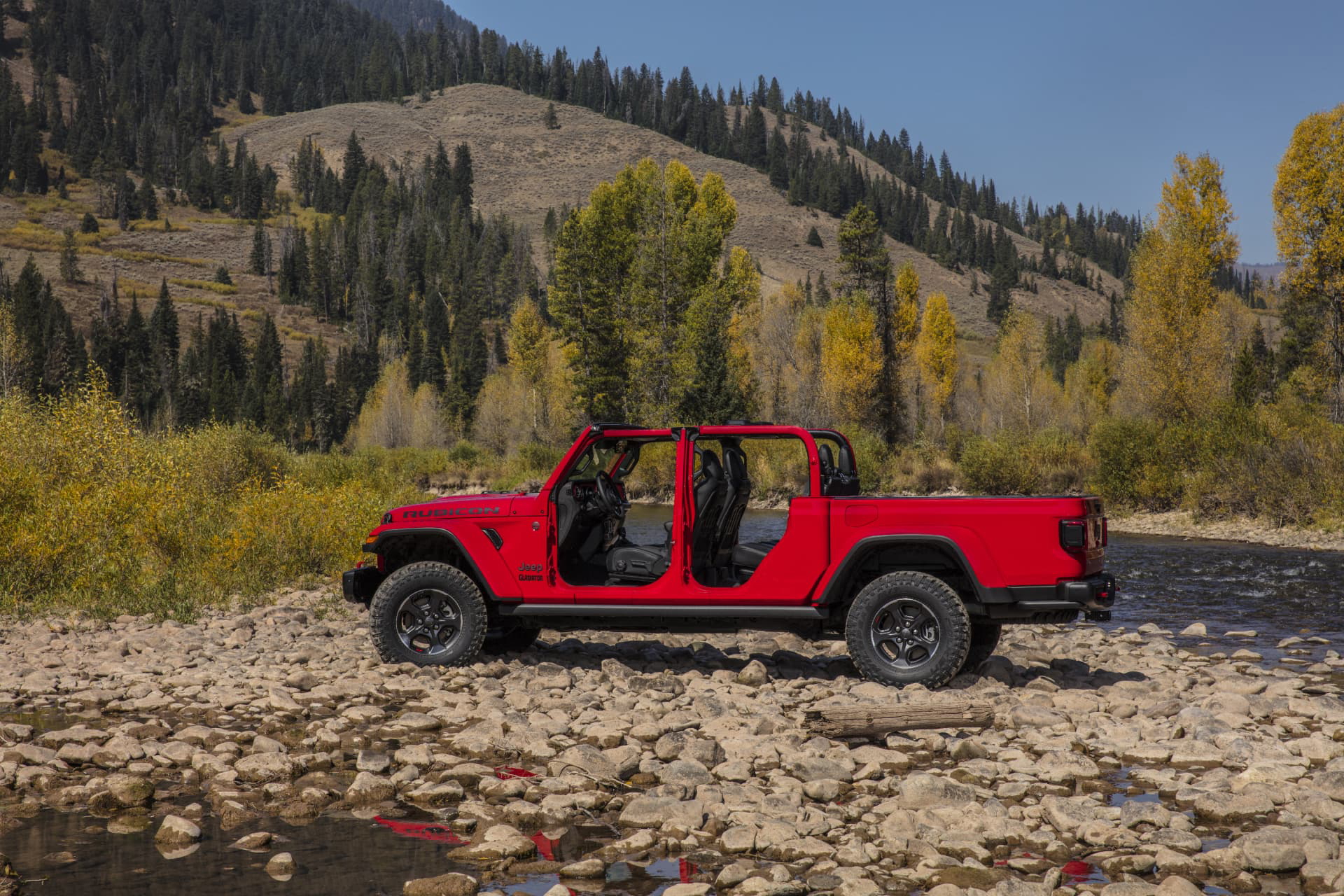 Vista lateral del Jeep Gladiator en un entorno natural, destacando su capacidad todoterreno.
