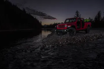 Vista lateral del Jeep Gladiator dominando terrenos adversos al anochecer.
