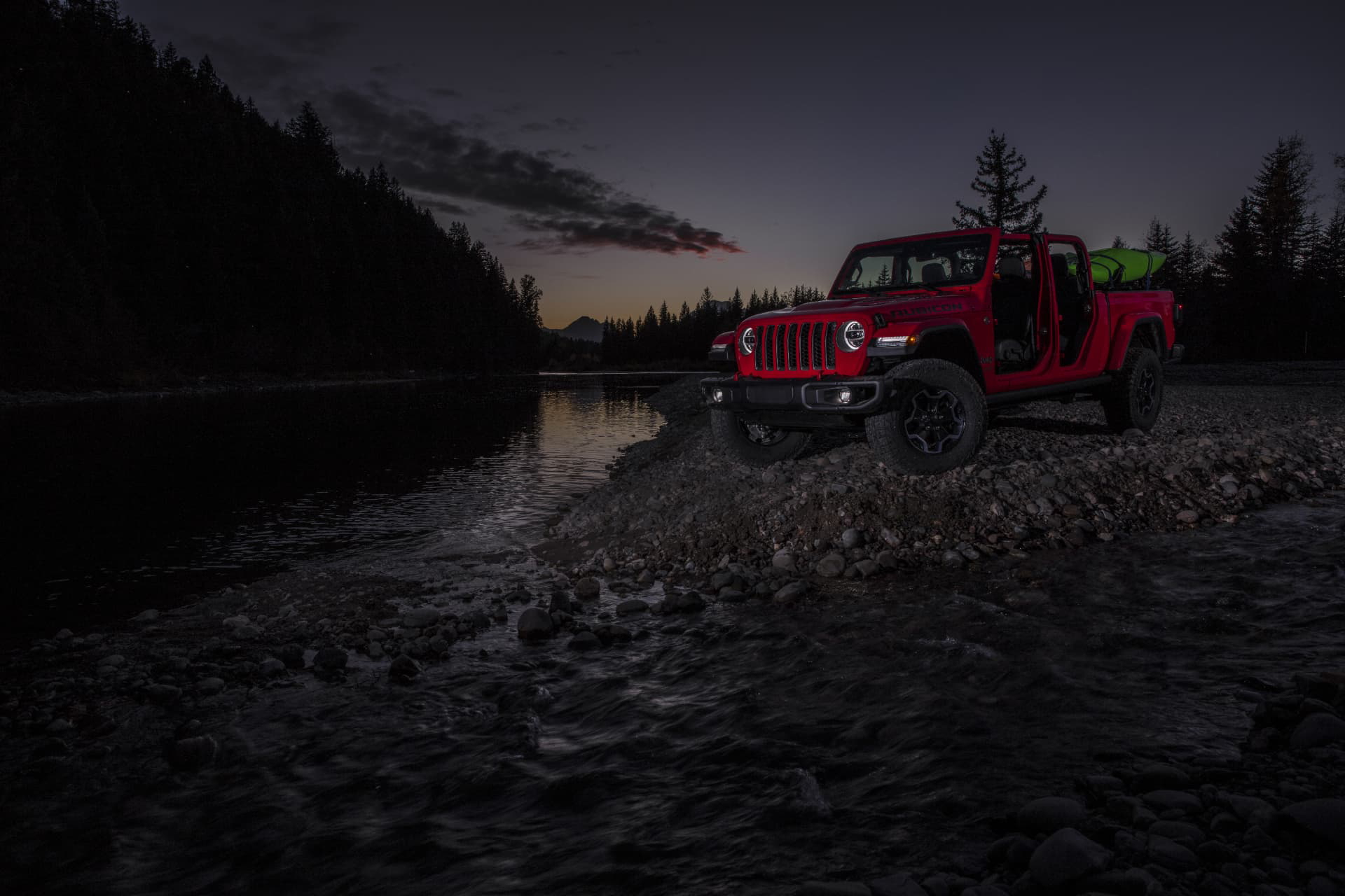 Vista lateral del Jeep Gladiator dominando terrenos adversos al anochecer.