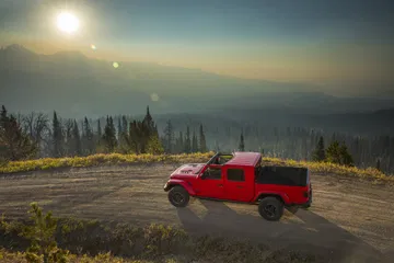 Jeep Gladiator en paisaje montañoso al atardecer, vista lateral completa.