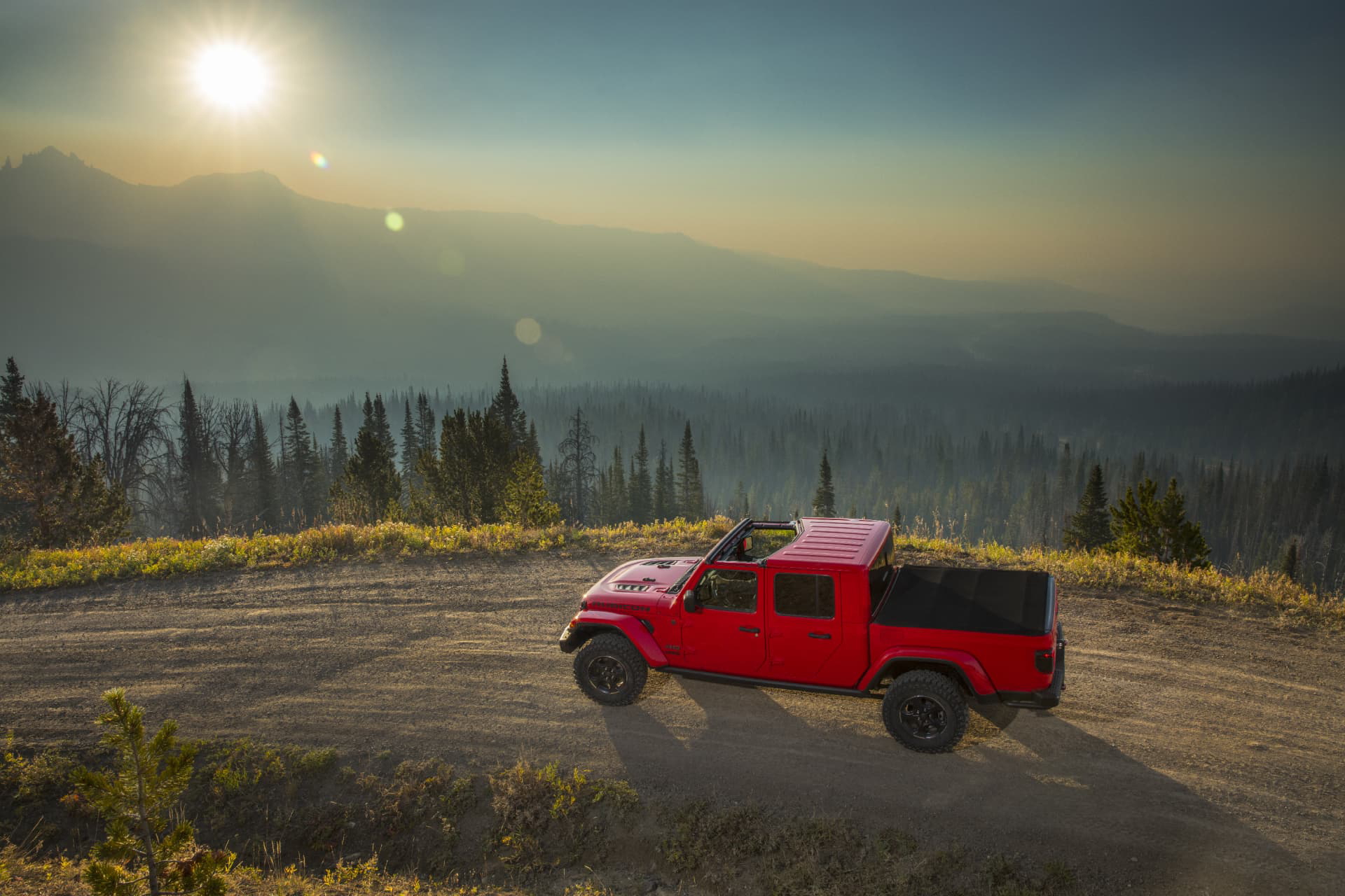Jeep Gladiator en paisaje montañoso al atardecer, vista lateral completa.