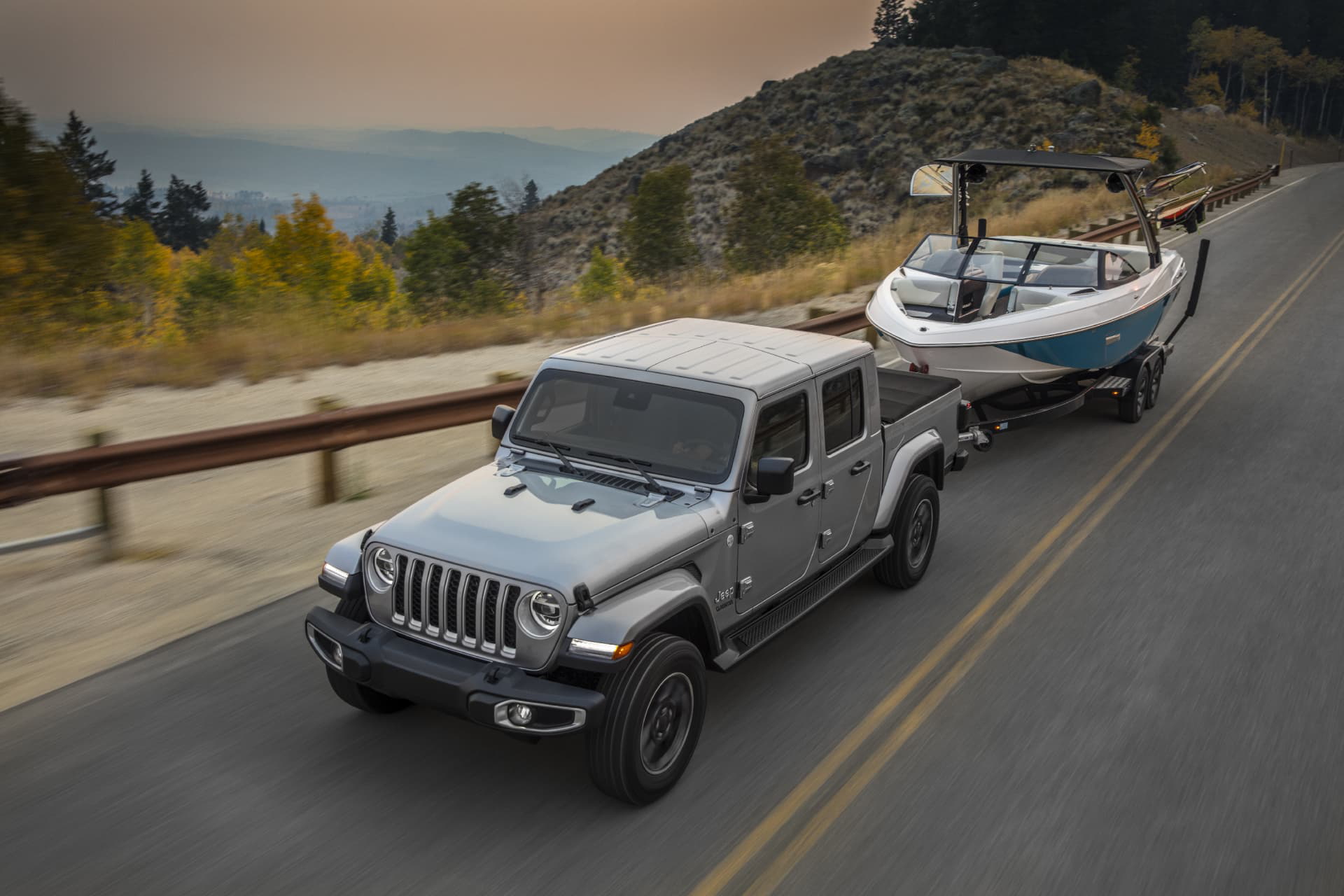 Jeep Gladiator remolcando un bote por carretera, destacando su capacidad de arrastre.