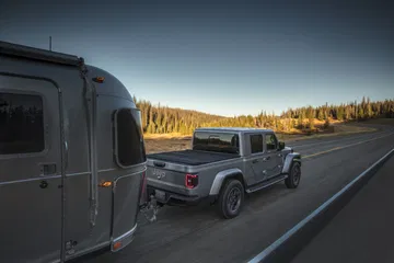 Vista trasera lateral del Jeep Gladiator remolcando una caravana en carretera.