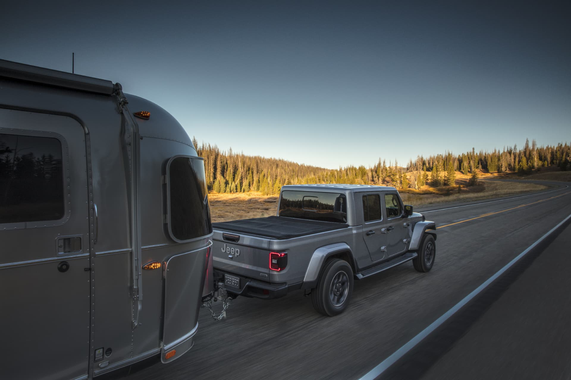 Vista trasera lateral del Jeep Gladiator remolcando una caravana en carretera.