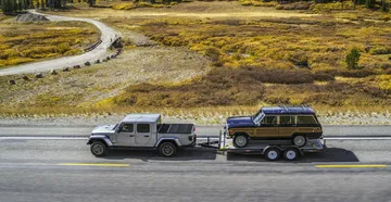 Vista aérea de un Jeep Gladiator remolcando un remolque por una carretera asfaltada.