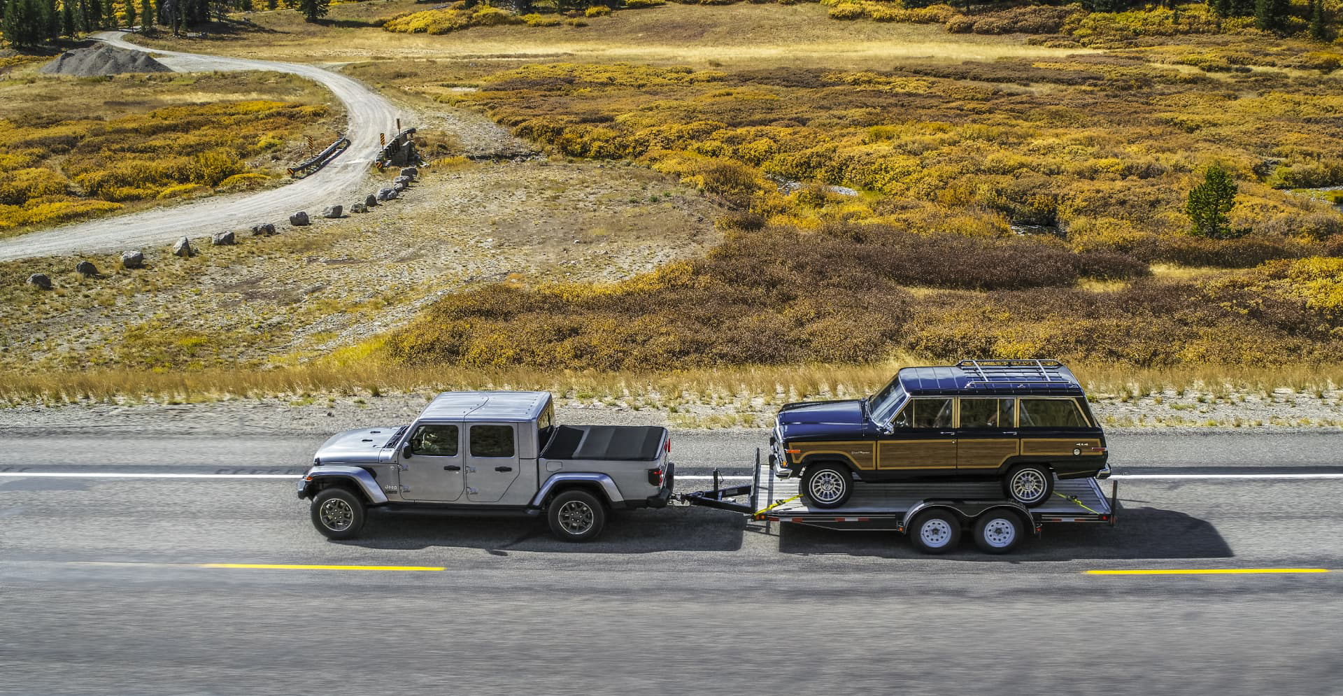 Vista aérea de un Jeep Gladiator remolcando un remolque por una carretera asfaltada.