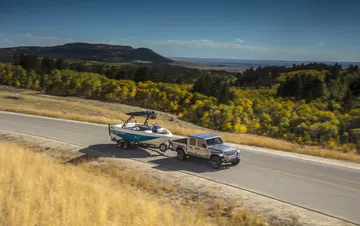 Vista lateral del Jeep Gladiator remolcando una lancha en carretera abierta