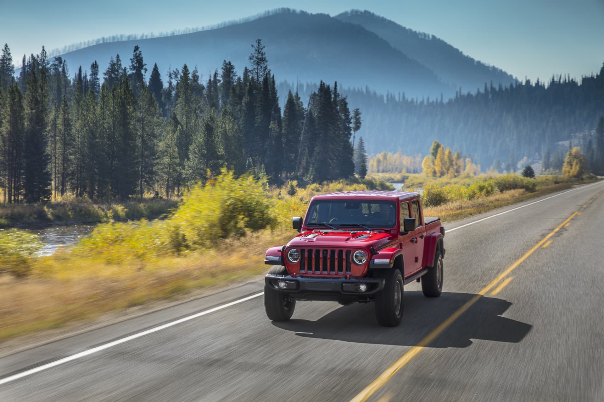 Jeep Gladiator avanzando por carretera con paisaje forestal al fondo