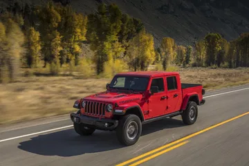 Jeep Gladiator en movimiento mostrando su línea lateral y diseño robusto.