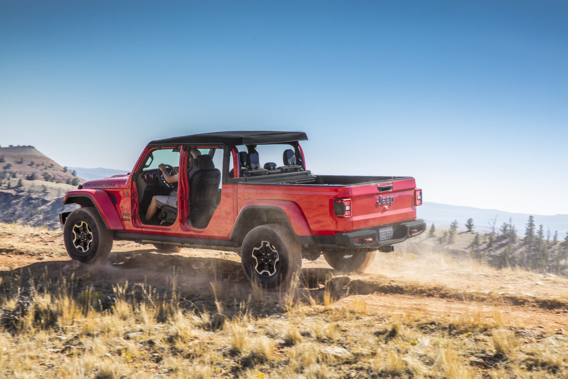 Vista lateral de un Jeep Gladiator rojo superando terreno montañoso