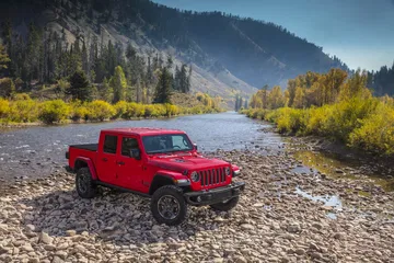 Vista lateral del Jeep Gladiator en rojo destacando su capacidad todoterreno.