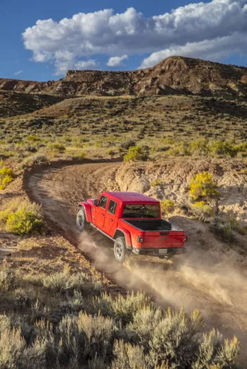 Vista dinámica lateral y trasera del Jeep Gladiator en acción por caminos de montaña