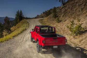 Vista lateral trasera del Jeep Gladiator rojo en camino de montaña