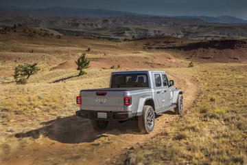 Jeep Gladiator en acción por terreno desértico, demostrando sus capacidades off-road.