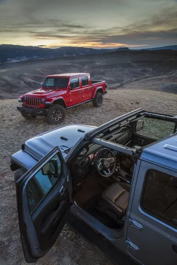 Vista lateral del Jeep Gladiator con techo parcialmente descubierto en terreno rocoso.
