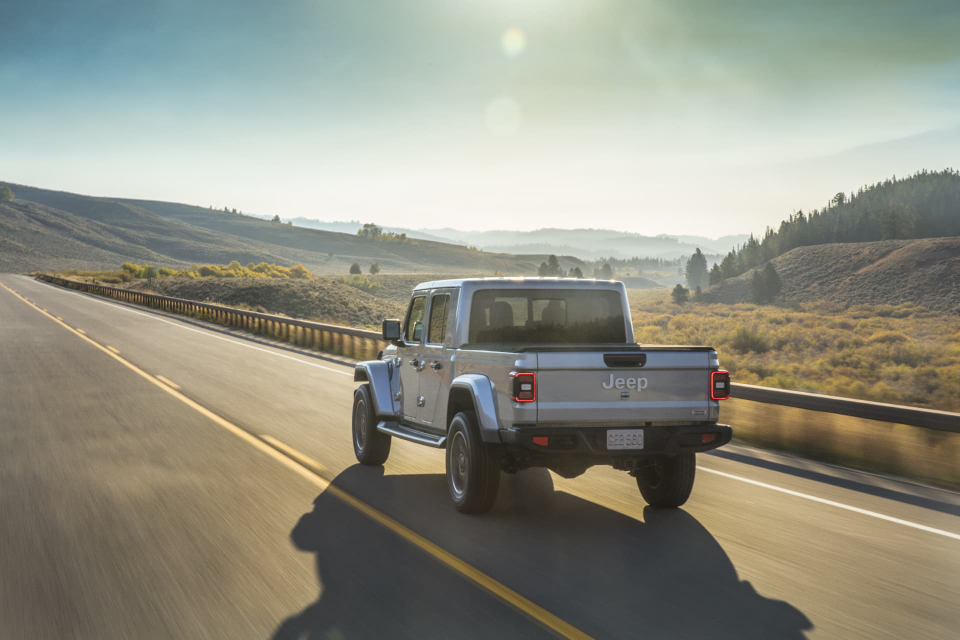 Vista trasera y lateral del Jeep Gladiator rodando sobre carretera al atardecer.