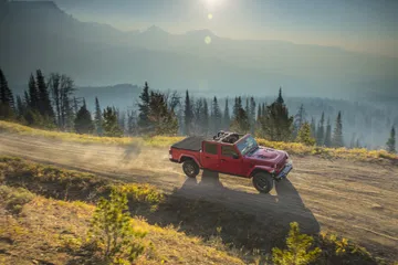 Jeep Gladiator mostrando su capacidad off-road en terreno montañoso al atardecer.