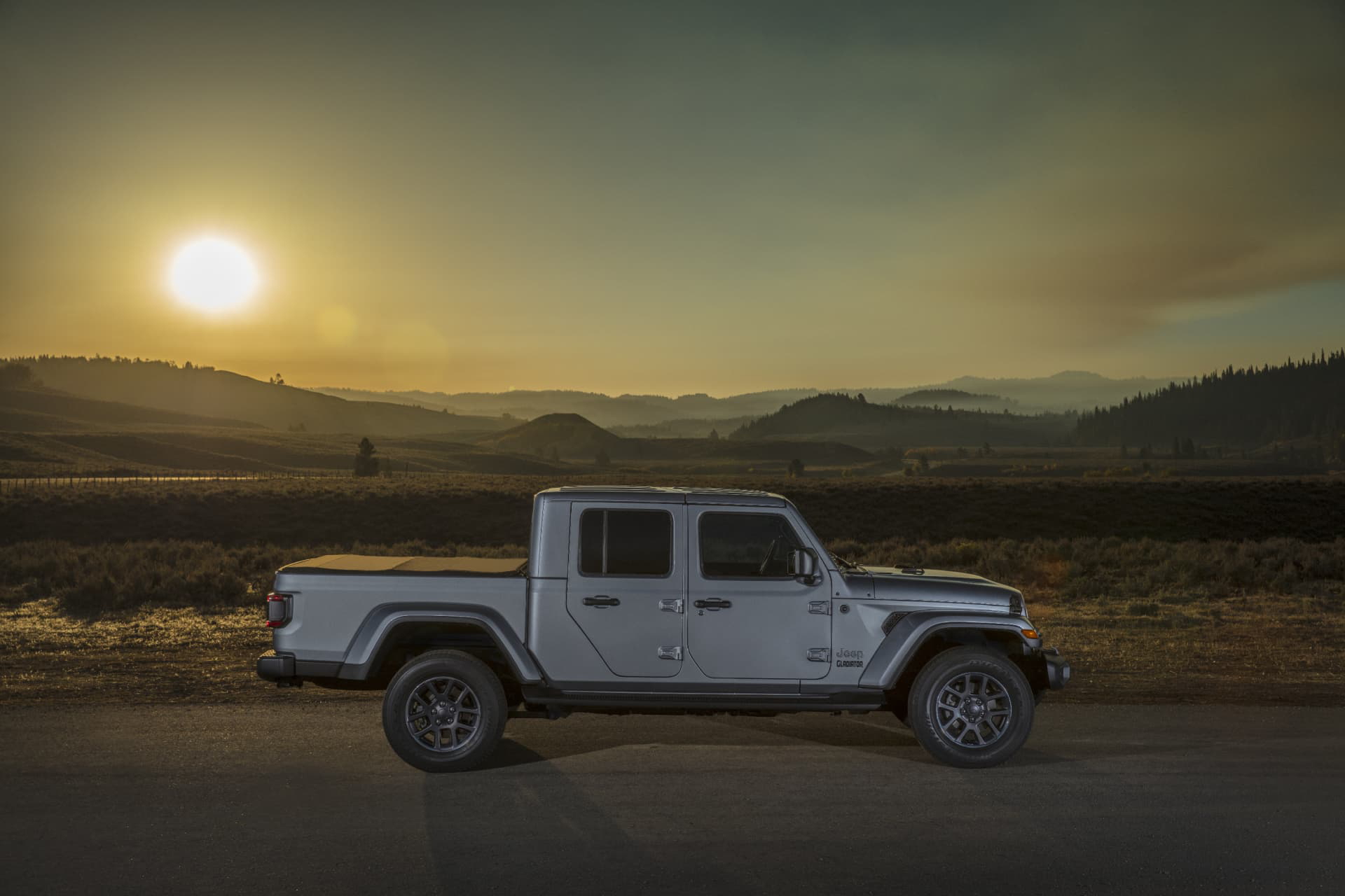 Jeep Gladiator avanzando por terreno abierto al atardecer, mostrando su imponente diseño lateral.