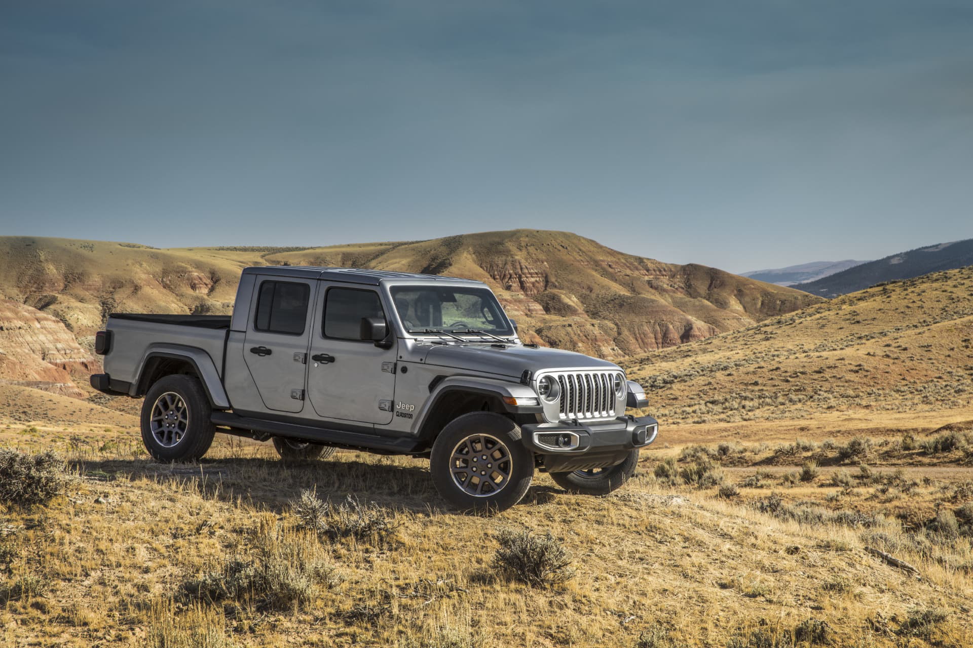 Vista lateral de un Jeep Gladiator en un entorno de campo abierto, mostrando su capacidad off-road.