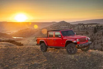 Vista lateral del Jeep Gladiator superando terrenos accidentados al atardecer.