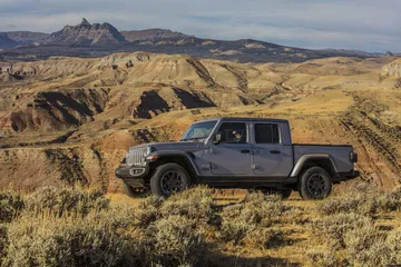 Vista lateral del Jeep Gladiator superando terreno accidentado, mostrando su capacidad off-road.