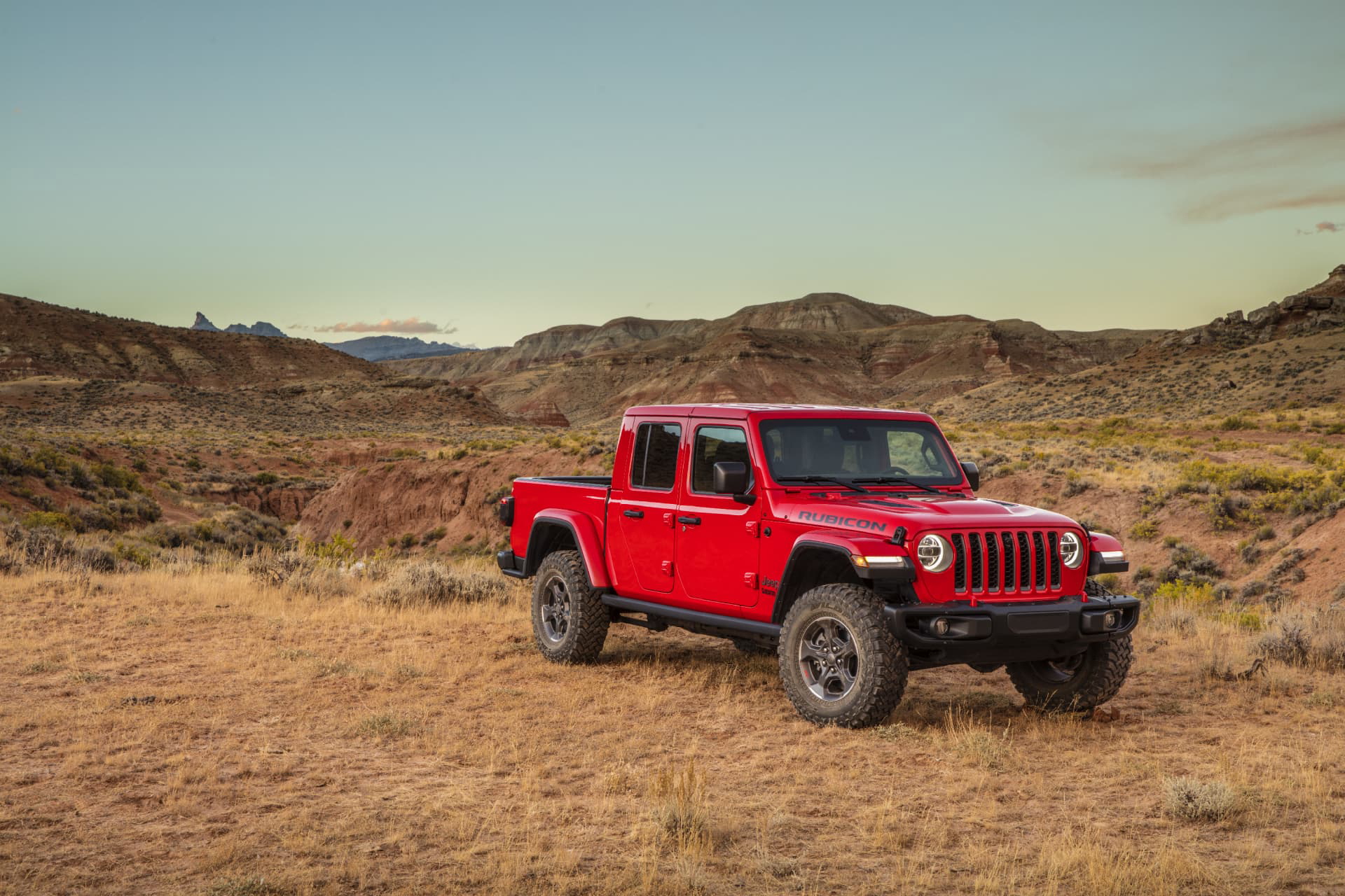 Vista lateral del Jeep Gladiator sobre terreno montañoso, destacando su capacidad todoterreno.