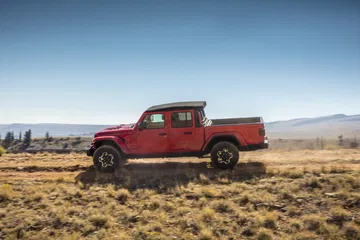 Vista lateral del Jeep Gladiator en terreno rugoso, exhibiendo su capacidad todoterreno.