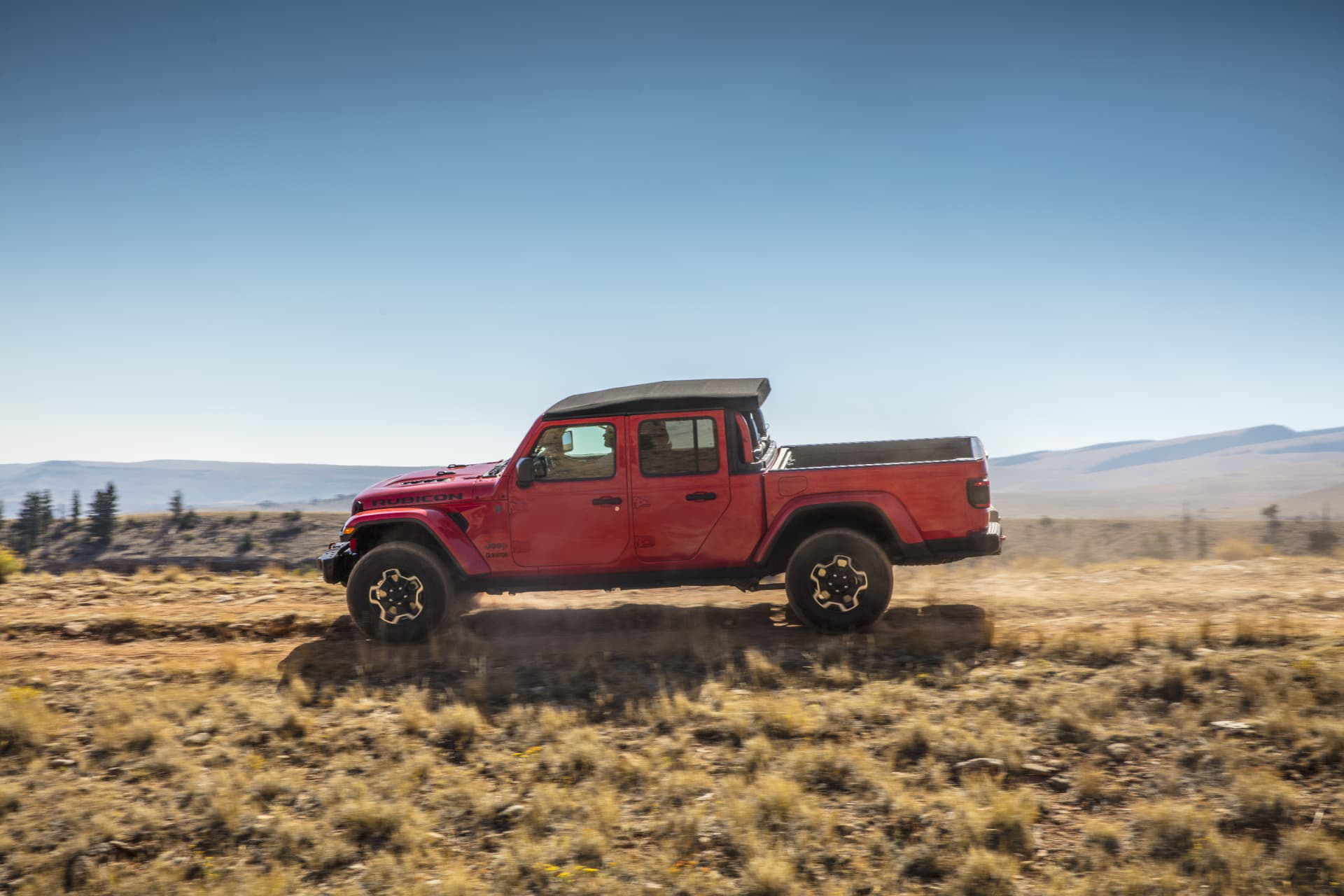 Vista lateral del Jeep Gladiator en terreno rugoso, exhibiendo su capacidad todoterreno.