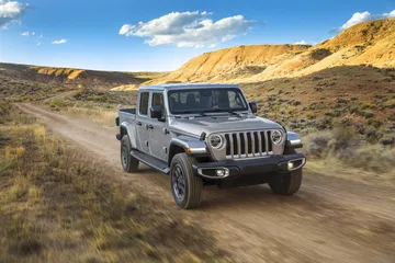 Jeep Gladiator avanzando por terreno rústico, mostrando su capacidad todoterreno.