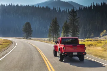 Jeep Gladiator capturado desde atrás en un entorno natural, mostrando su robustez.