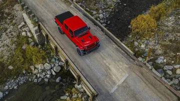 Vista aérea de un Jeep Gladiator rojo transitando por un puente.