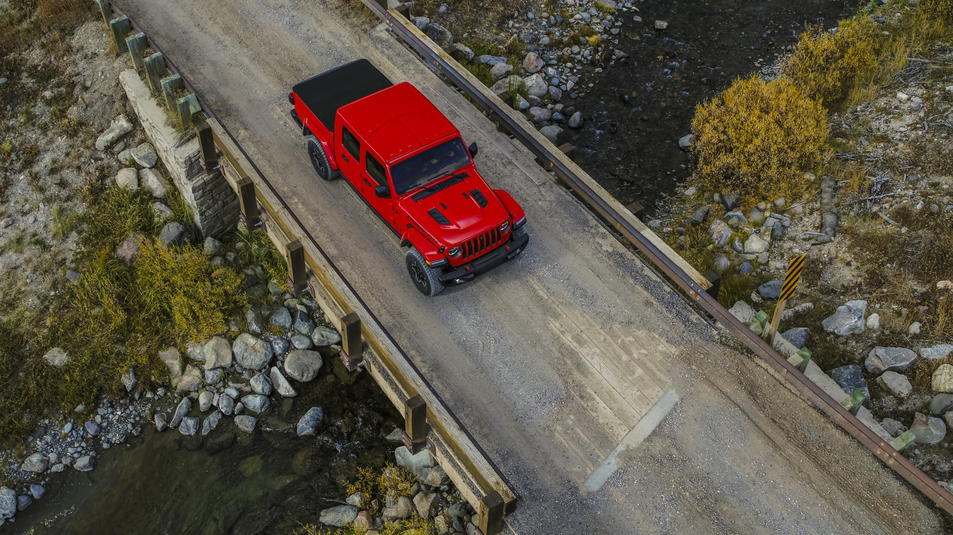 Vista aérea de un Jeep Gladiator rojo transitando por un puente.