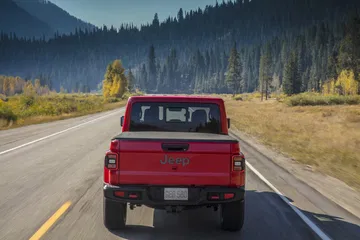 Vista trasera del Jeep Gladiator rodando por carretera con paisaje boscoso.