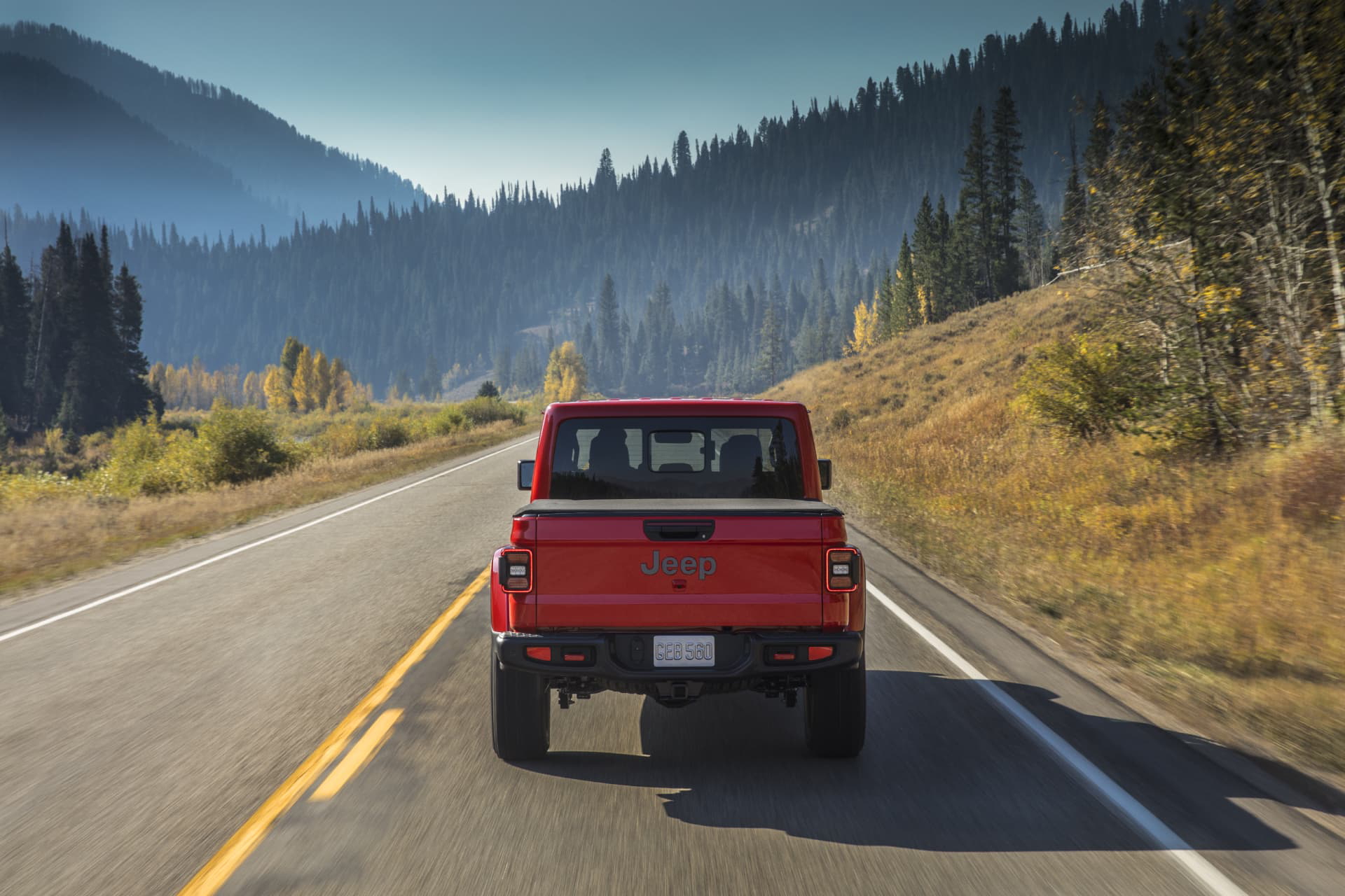 Jeep Gladiator visto desde atrás mientras recorre una carretera entre montañas.