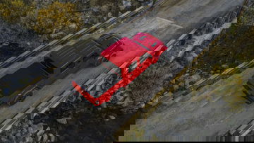 Vista aérea de un Jeep Gladiator rojo circulando por una vía elevada.